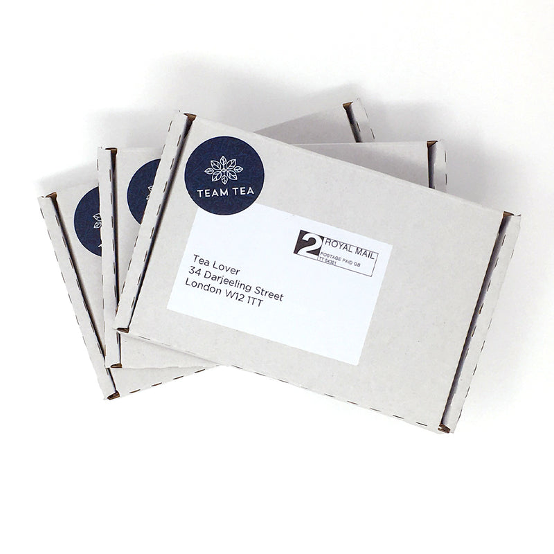 Three white Tea Club subscription boxes with blue and black branding text on them, placed on a white surface.