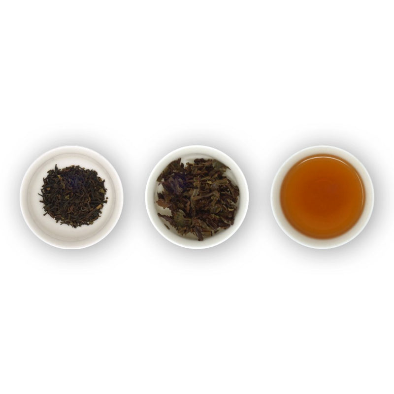 Three white bowls arranged in a row, with the left bowl containing dry black tea leaves, the middle bowl showing the same leaves after brewing, and the right bowl presenting a cup of brewed tea.