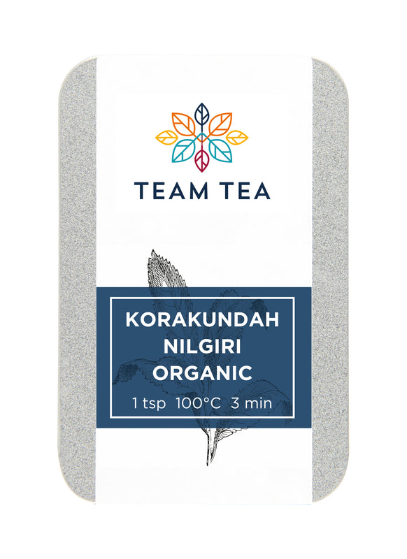 A silver metal tin against a white background. The tin is labelled Korakundah Nilgiri Black and contains loose-leaf black tea leaves from India.