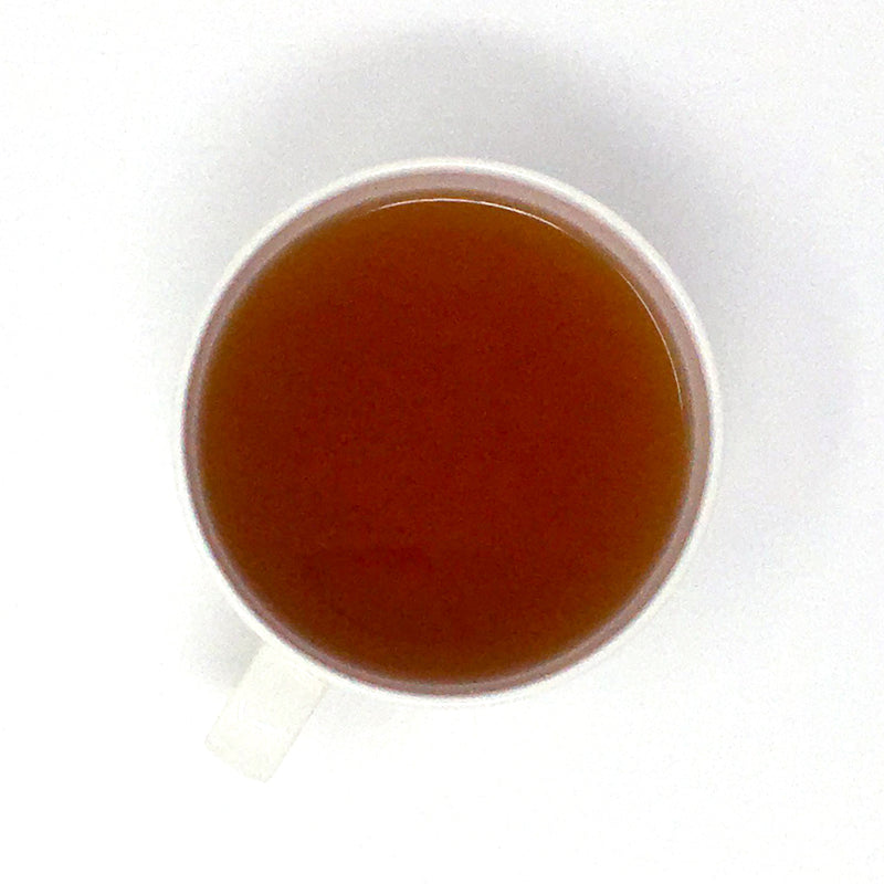 A close-up image of a single white teacup of brewed black tea on a white background.