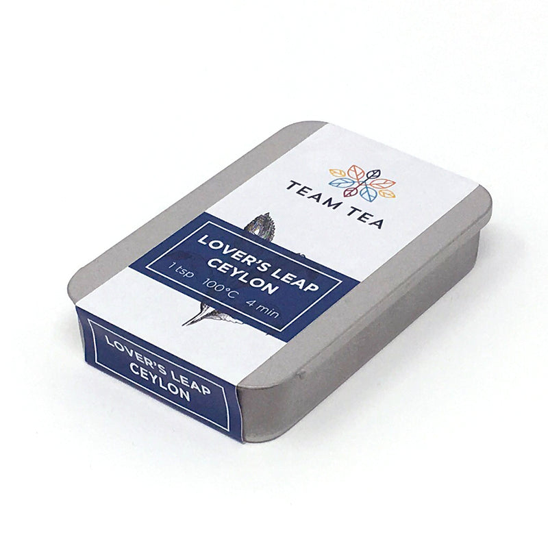 A silver metal tin with sliding lid and navy blue paper label. The description reads Lover's Leap Ceylon
