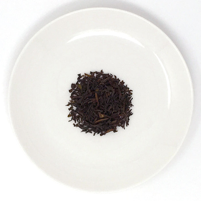 A close-up of a white plate with a pile of loose-leaf black teas from Sri Lanka
