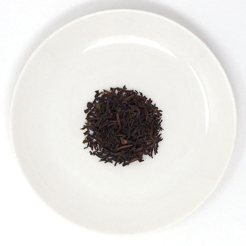 A close-up of a white plate with a pile of loose-leaf black teas from Sri Lanka