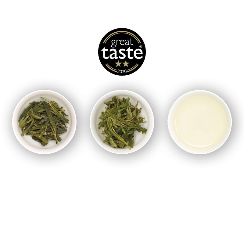 Three white bowls containing loose-leaf green tea leaves and a cup with brewed tea liquid, with a 'Great Taste Awards' winners badge displayed above.