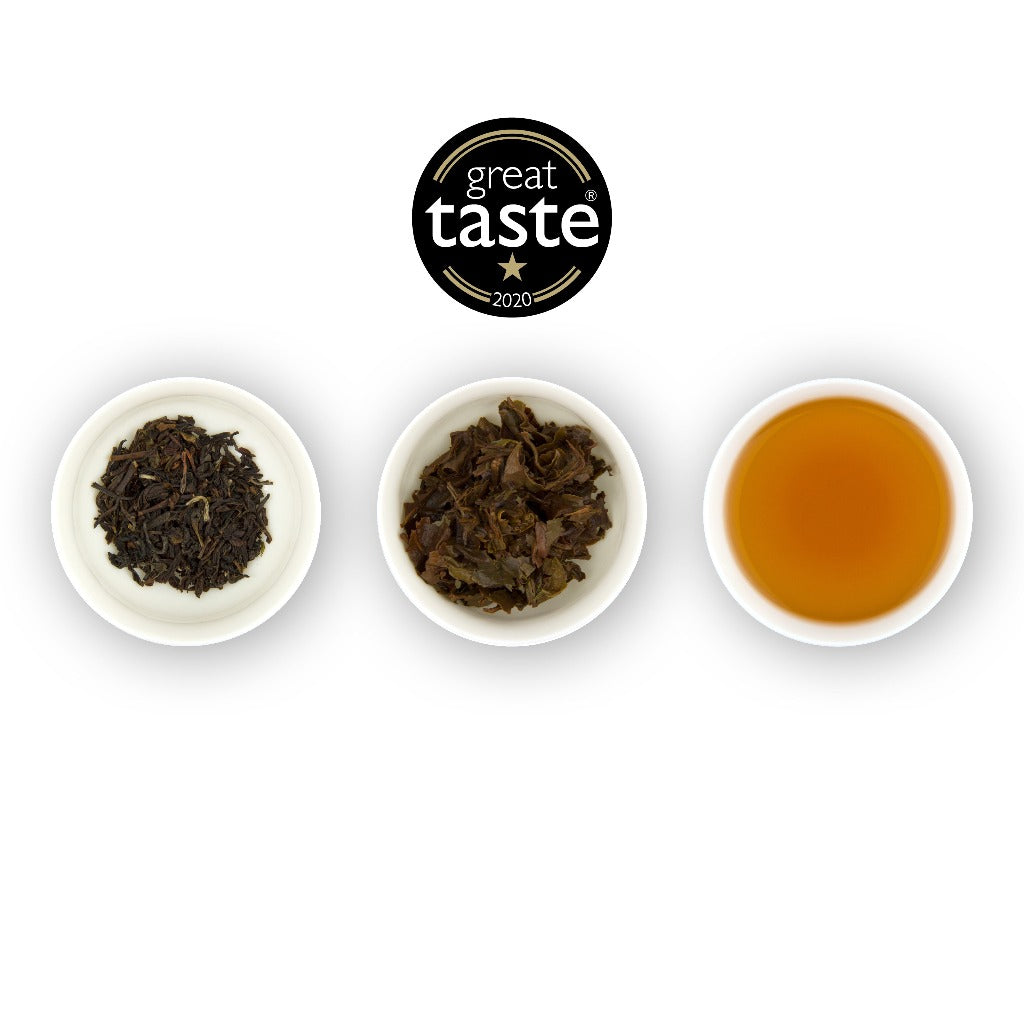 Three circular bowls arranged in a row, with the left bowl showing dried black tea leaves, the middle bowl showing brewed black tea leaves, and the right bowl showing the brewed tea liquid, all against a white background. Above the plates is a logo for 'Great Taste'.