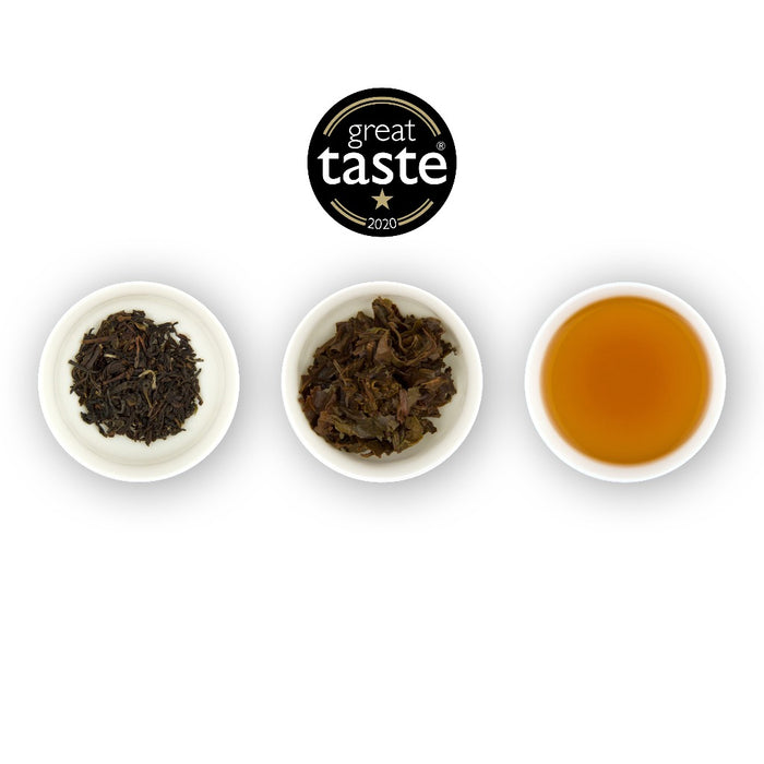 Three circular bowls arranged in a row, with the left bowl showing dried black tea leaves, the middle bowl showing brewed black tea leaves, and the right bowl showing the brewed tea liquid, all against a white background. Above the plates is a logo for 'Great Taste'.