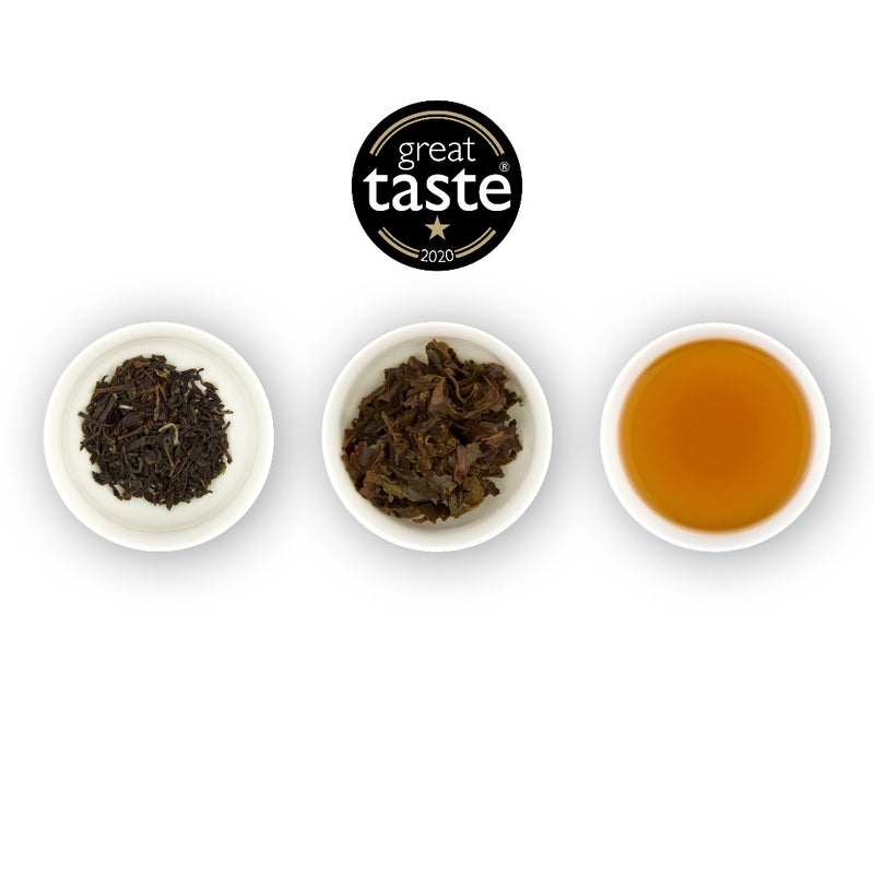 Three circular bowls arranged in a row, with the left bowl showing dried black tea leaves, the middle bowl showing brewed black tea leaves, and the right bowl showing the brewed tea liquid, all against a white background. Above the plates is a logo for 'Great Taste'.