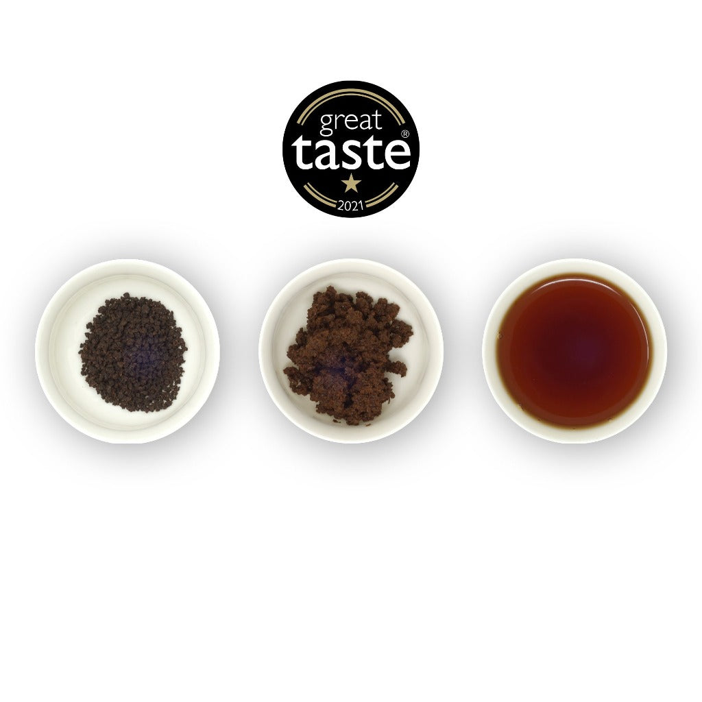 Three circular bowls, the first with dry black tea leaves, the second with loose tea leaves, and the third with brewed tea in a cup, indicating the brewing process. The Great Taste Awards badge is above