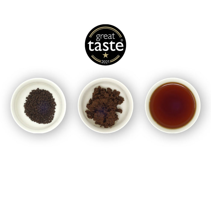 Three circular bowls, the first with dry black tea leaves, the second with loose tea leaves, and the third with brewed tea in a cup, indicating the brewing process. The Great Taste Awards badge is above