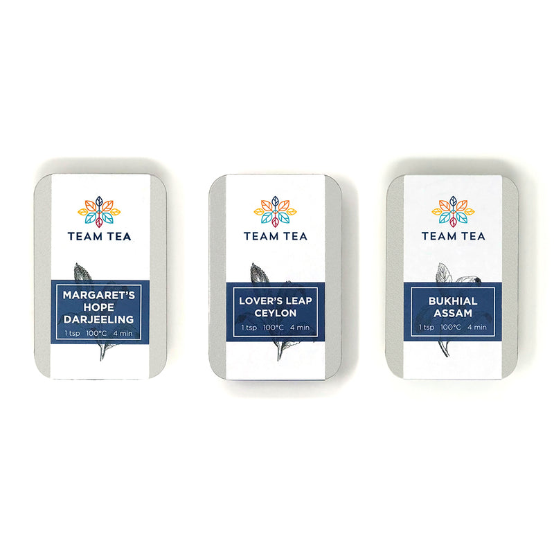 Three slide tins of Team Tea single estate selection, labeled as Margaret's Hope Darjeeling, Bukhial Assam, and Lover's Leap Ceylon, with the brand logo and product information visible.