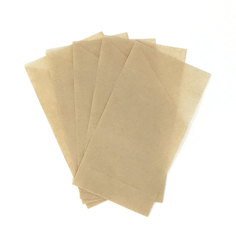 A stack of beige, rectangular, biodegradable paper tea filters