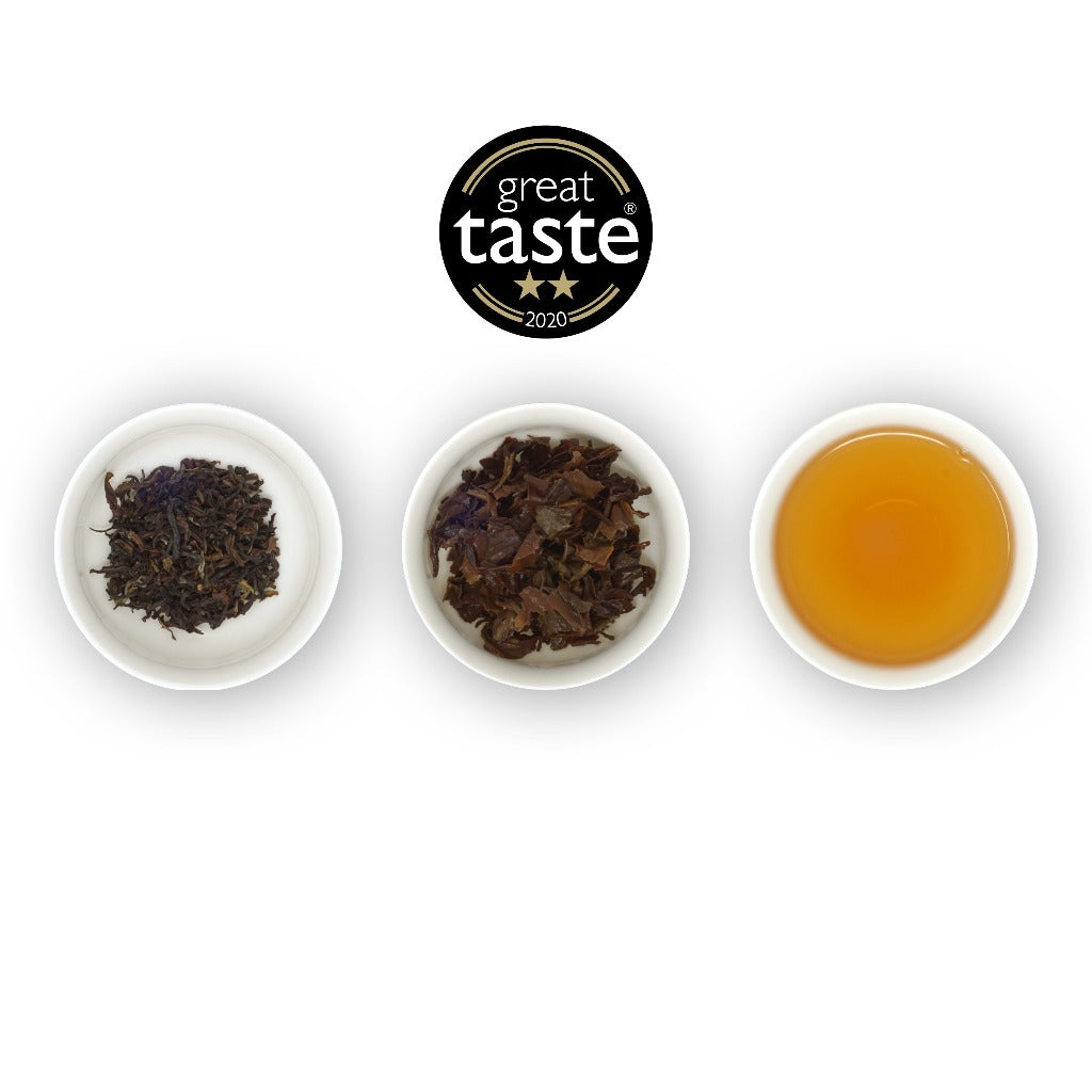 Three white bowls containing loose leaf black tea, with a logo of 'great taste awards' at the top center, and a bowl of brewed tea on the right.