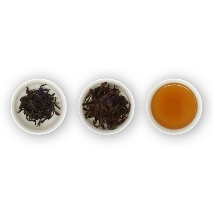 Three circular bowls arranged in a row, with the left bowl showing dried black tea leaves, the middle bowl showing brewed black tea leaves, and the right bowl showing the brewed tea in a cup.