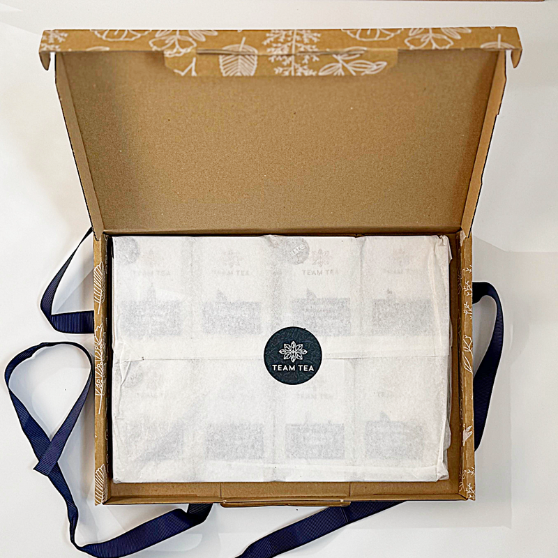 Open cardboard box with tea bags inside, featuring a visible brand logo.