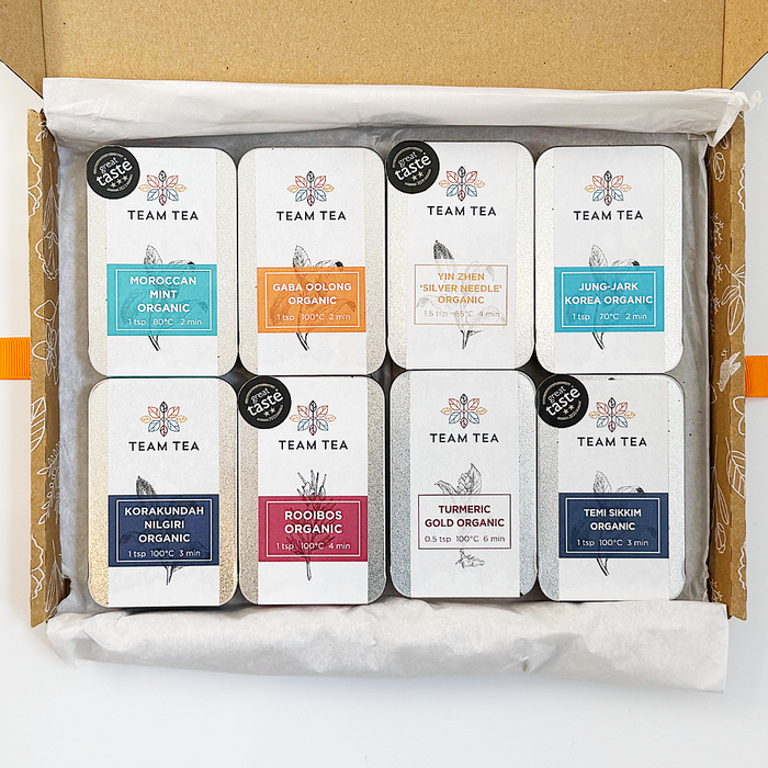 Box of Team Tea slide tins with various tea types on a white background