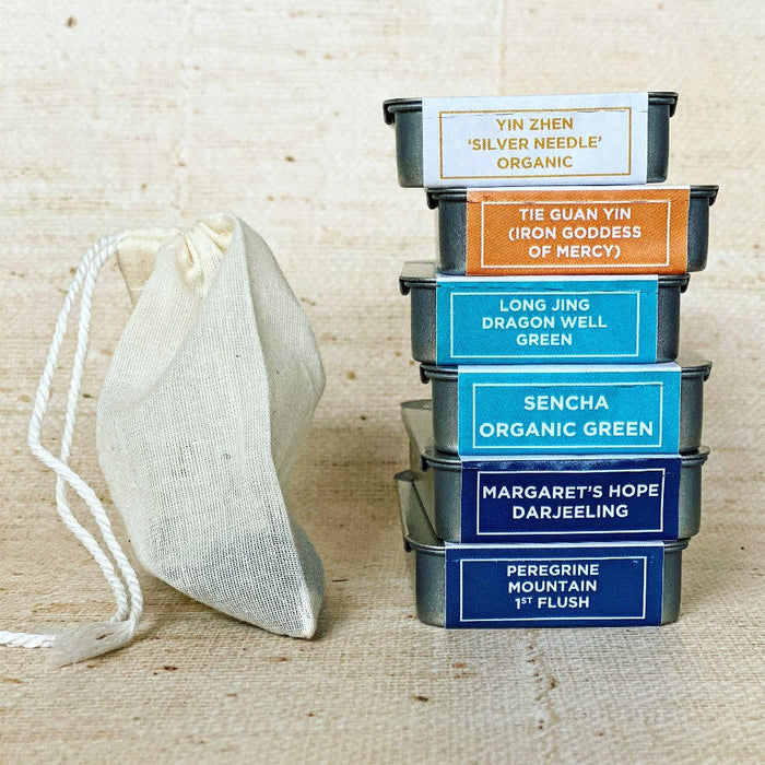 Image showing a stack of 6 slide tins of tea next to a reusable unbleached cotton tea bag.